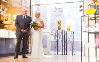 Bride and father in art gallery setting.