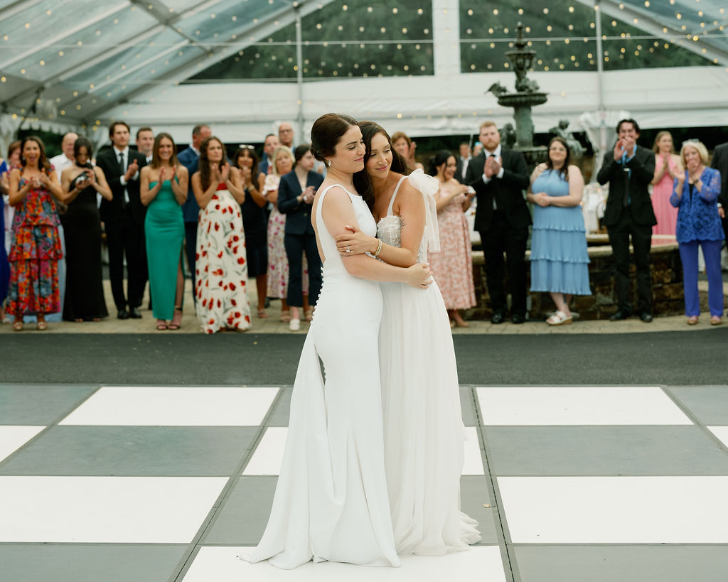 Brides dancing in a clear tent with checkboard dance floor 