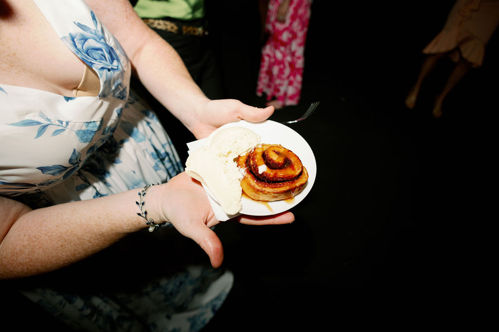woman in blue and white dressing holding cinnamon roll